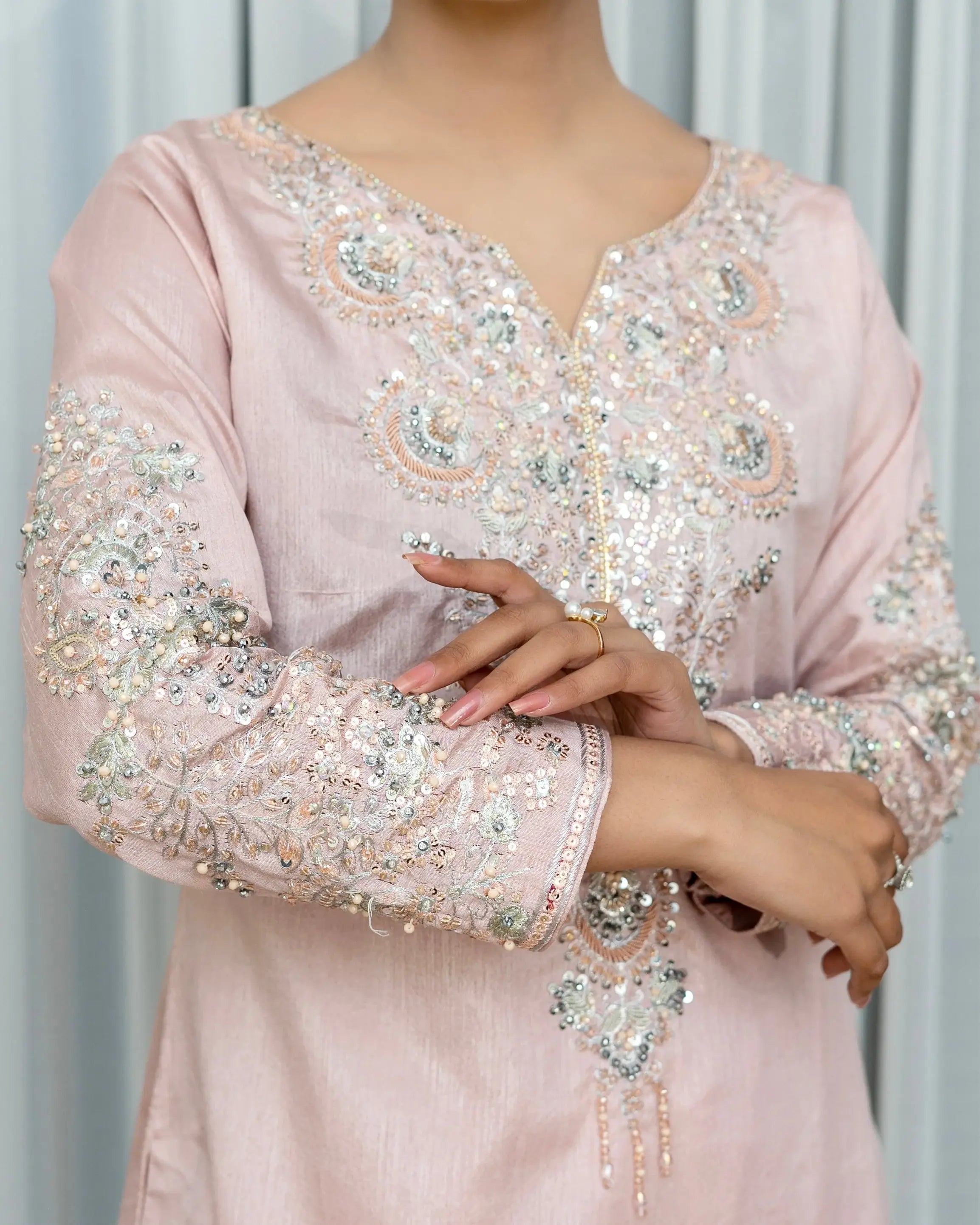 Pink embroidered dress with intricate detailing on a plain background