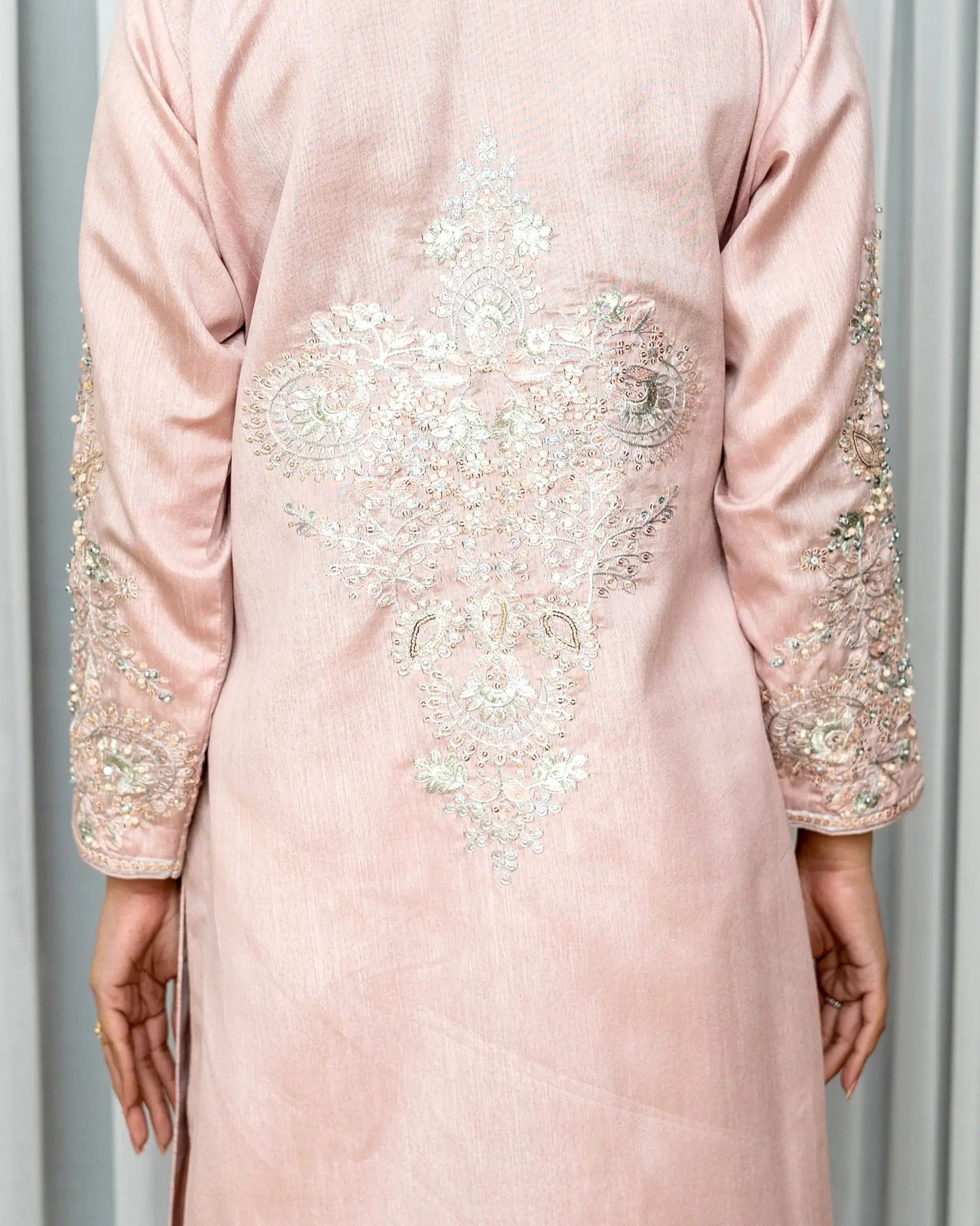 Pink dress with intricate beadwork on a neutral background