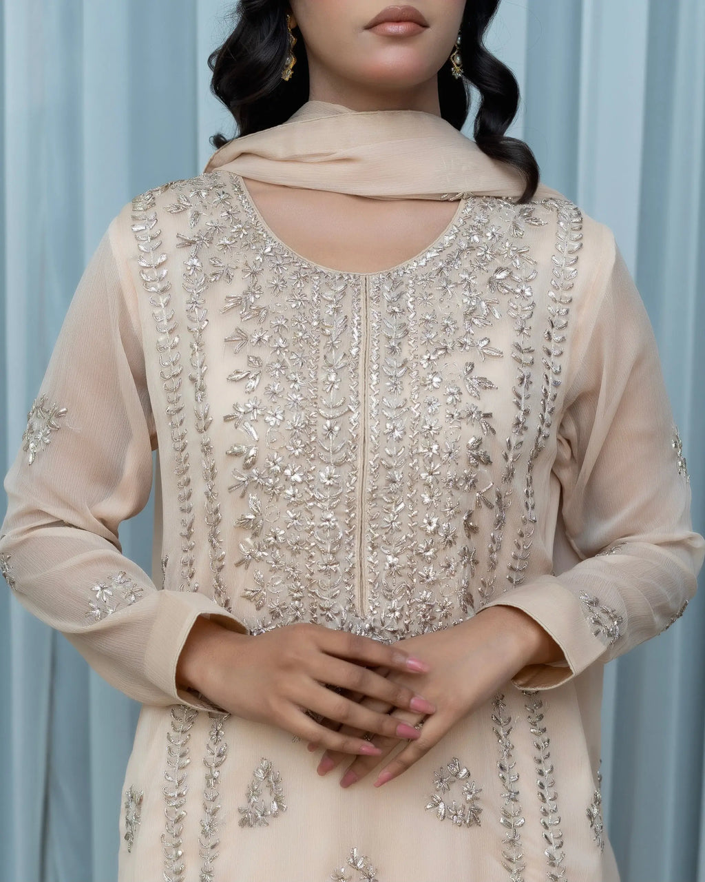 Beige embroidered outfit with a plain background