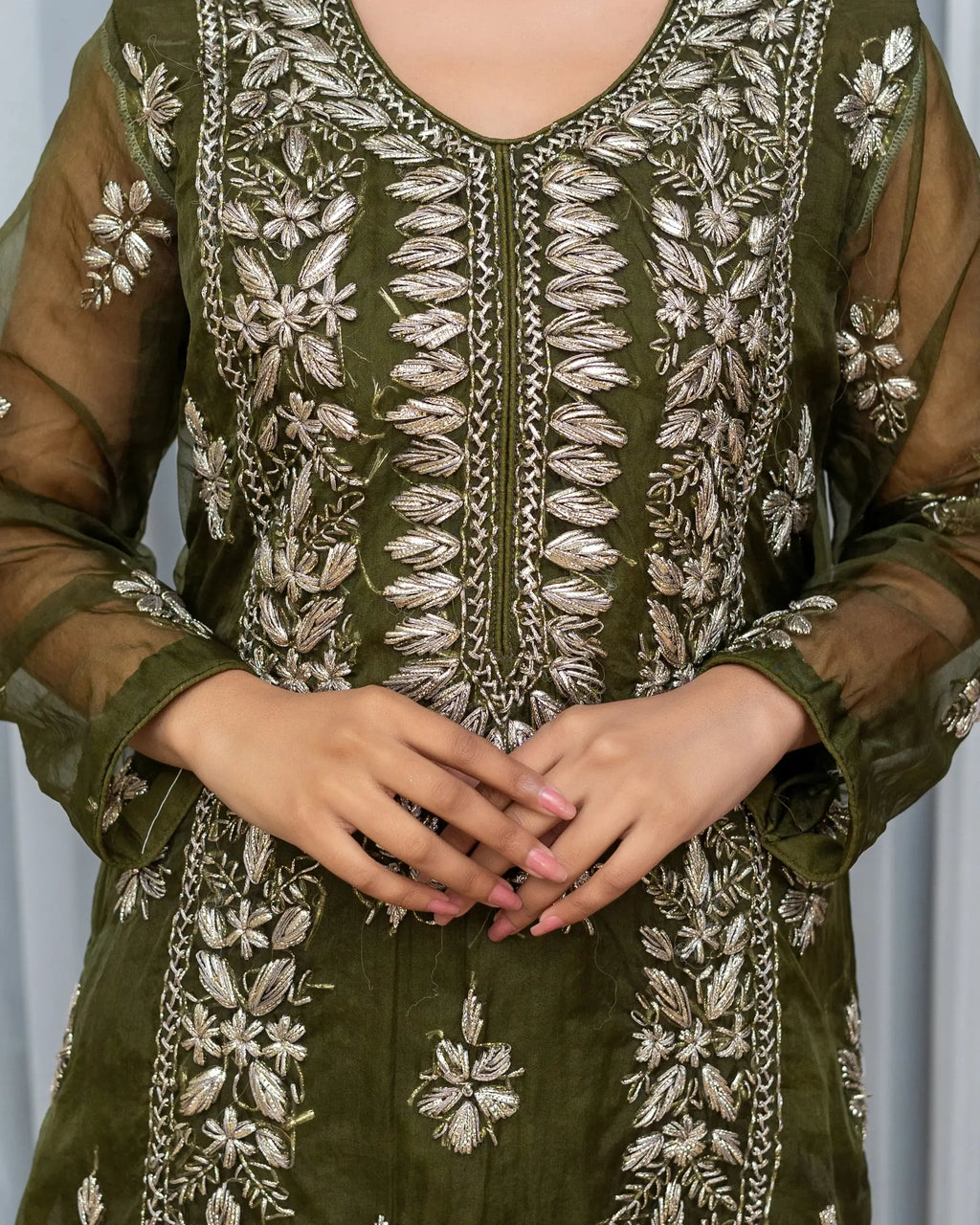 Green embroidered traditional outfit with floral patterns on a plain background