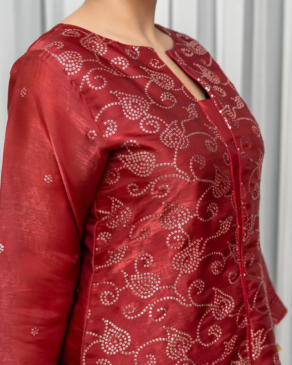 Red embroidered blouse with intricate patterns on a white background