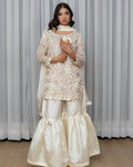 Woman wearing a traditional outfit with a lace top and white pants against a striped curtain background