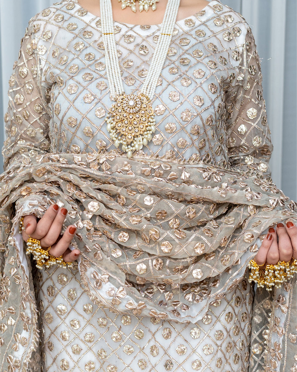 Elegant silver and gold embroidered traditional outfit with jewelry.