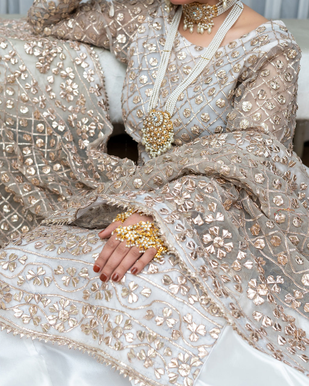 Elegant silver and gold embroidered traditional outfit with jewelry.